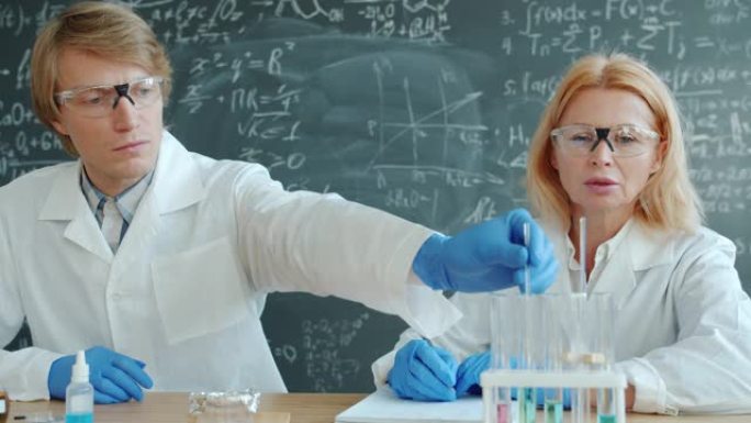 在实验室进行化学实验的男女科学家交谈