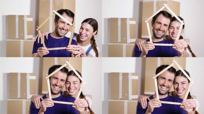 一对刚刚买房并正在搬家的恋爱夫妇的肖像。新娘和新郎微笑着，手里拿着房子形状的仪表。