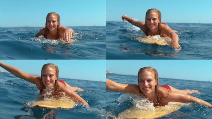 肖像: 微笑的冲浪女孩玩得开心，游泳到队伍里去捕捉波浪。
