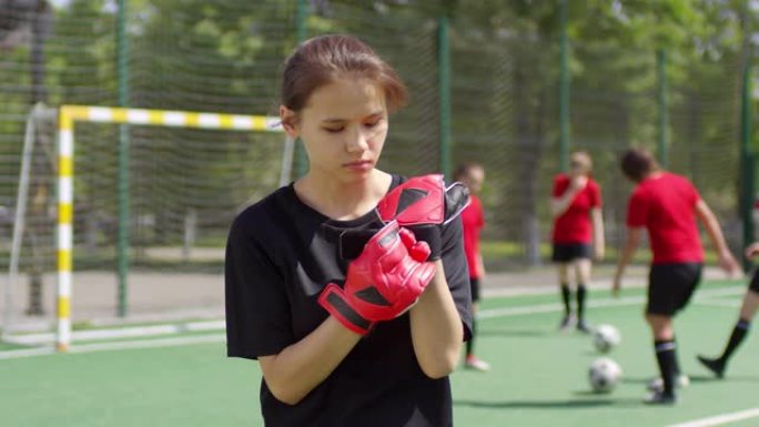 年轻的女足球运动员戴上守门员手套