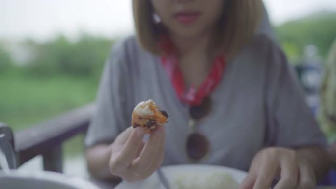 慢动作-年轻的亚洲女性在餐厅吃虾海鲜，青少年女性在吃食物时感到快乐。女人吃海鲜概念。