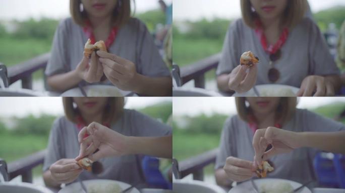 慢动作-年轻的亚洲女性在餐厅吃虾海鲜，青少年女性在吃食物时感到快乐。女人吃海鲜概念。