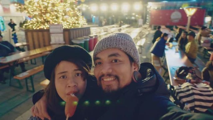 亚洲游客夫妇在日本的圣诞节市场博览会上自拍。