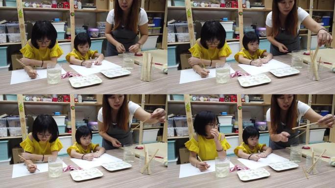 一名亚洲中国女美术老师在美术课上教2名中国女青年学生水彩画和着色