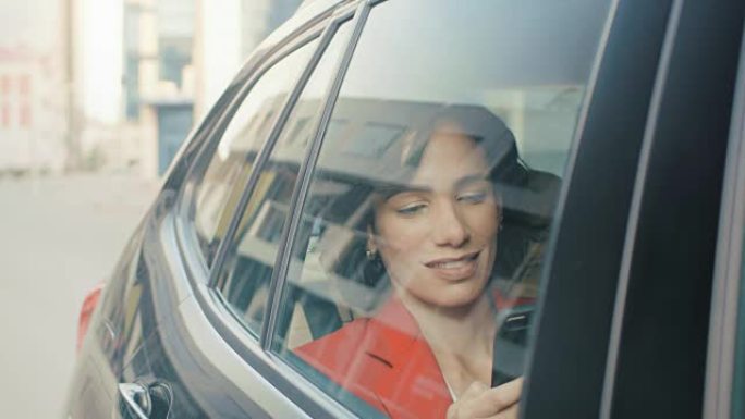 美丽的女人坐在汽车上，坐在乘客后座上使用智能手机，浏览互联网，与朋友聊天。从车外拍摄的摄像机。