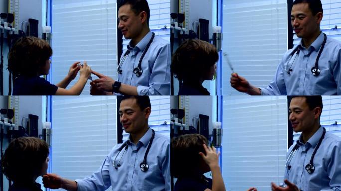 年轻的亚洲男医生在诊所4k向高加索男孩患者展示音叉的侧视图