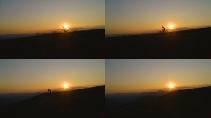 剪影: 无法辨认的人在日落时骑着山地自行车下坡。