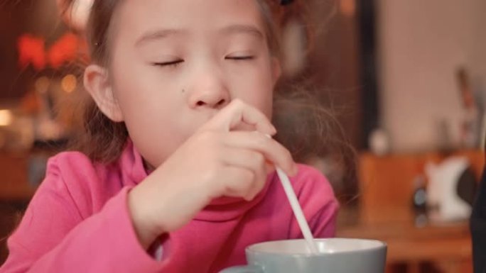 SLO MO可爱的亚洲小女孩用吸管喝水