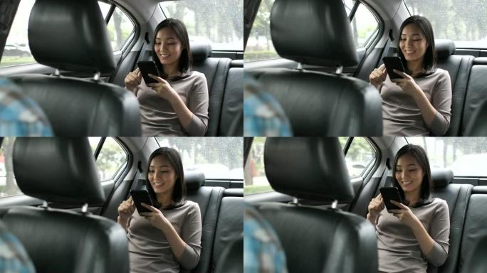 亚洲人在汽车后座上使用智能手机