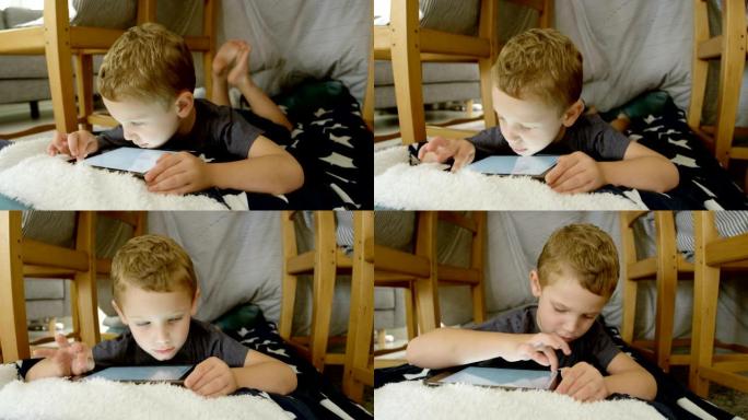 在舒适的家庭4k中使用数字平板电脑的可爱高加索男孩的前视图