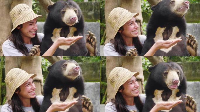 一个女人怀里抱着一只熊，给她喂食。