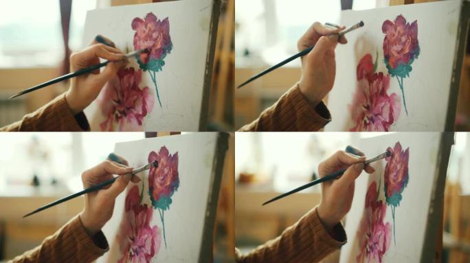 肮脏女孩的手握毛笔和画花的近距离拍摄美丽的静物画，独自在车间工作。创造力和艺术概念。