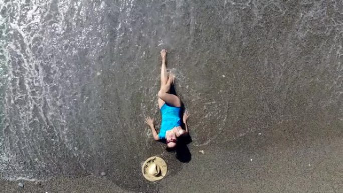 一个女人喜欢波浪，躺在海滩上。