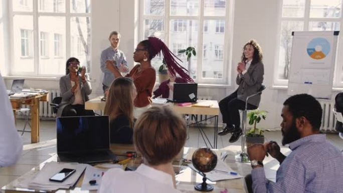 有趣快乐的非洲女商人在现代阁楼办公室做疯狂的庆祝舞蹈，同事分享成功