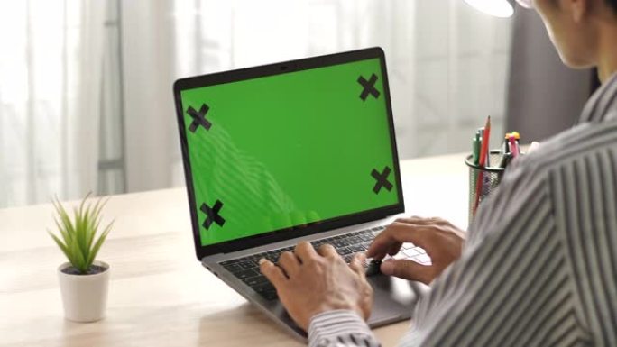 男人在家里的桌子上使用笔记本电脑的绿屏