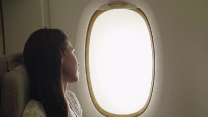 一个女人在飞机上放松，去度假，坐在舒适的座位上，从窗户上可以看到天空的云彩。