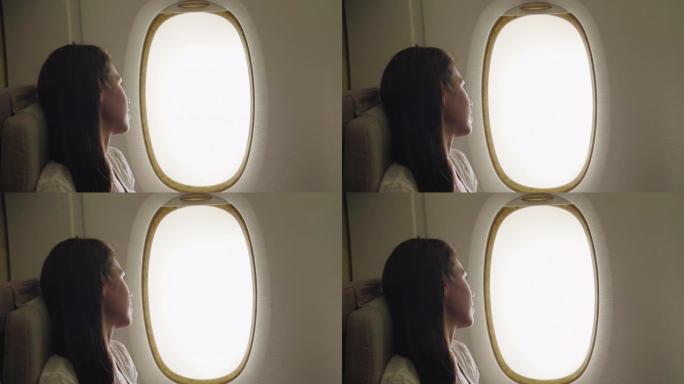 一个女人在飞机上放松，去度假，坐在舒适的座位上，从窗户上可以看到天空的云彩。