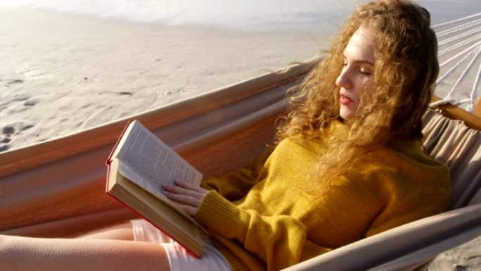 女人在4k海滩的吊床上看书