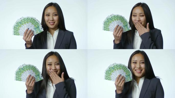 惊讶的亚洲女商人与欧元票据迷和微笑