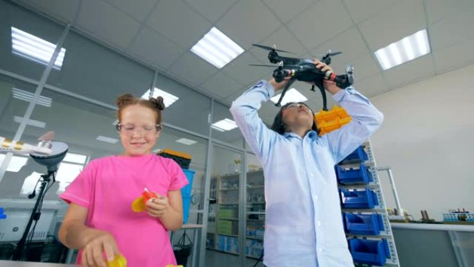 两个孩子在实验室里玩四轴飞行器，无人机