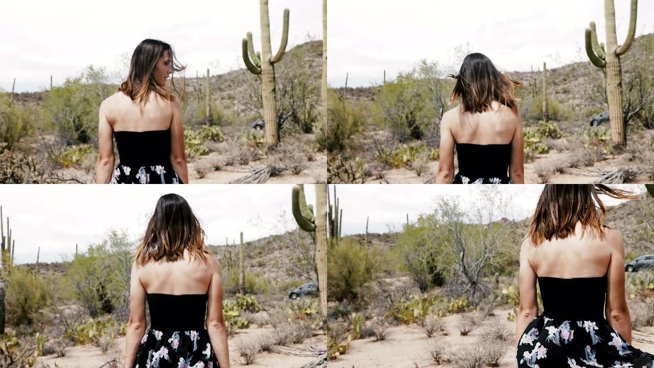 慢动作摄像机跟随年轻迷人的旅游女子，在仙人掌沙漠公园散步。