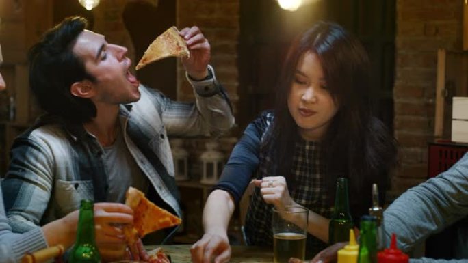 快乐的朋友在餐厅或酒吧吃意大利披萨和喝啤酒的慢动作