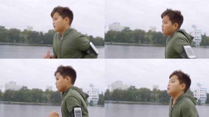 亚洲男孩，臂章上的智能手机在城市河边奔跑