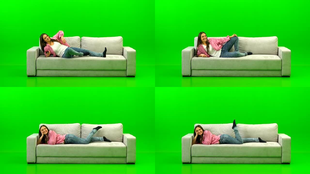 笑的女人躺在绿色背景上的沙发上