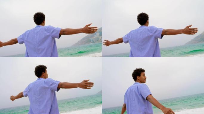 非洲裔美国男子站在海滩上的后视图，双臂伸出4k