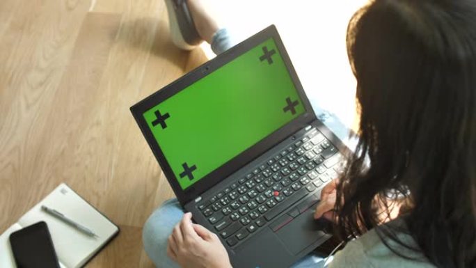 亚洲女性正在打字，看着绿屏笔记本电脑