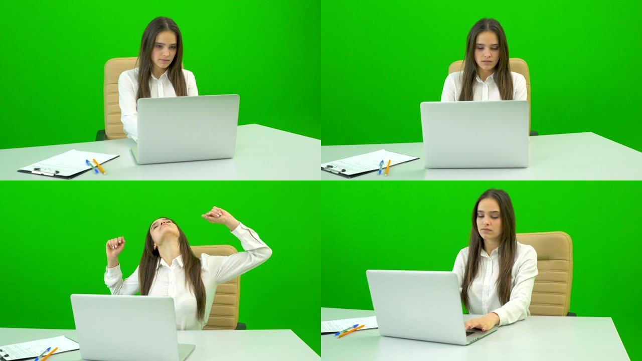 在绿色背景上的台式机上使用笔记本电脑的女人