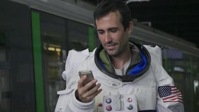 一名穿着衣服的宇航员使用智能手机打电话和发送信息。宇航员一边微笑，一边看着手中的电话。概念: 电话促