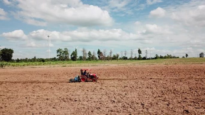 农民在农田和风力涡轮机的背景下耕作，农业机械