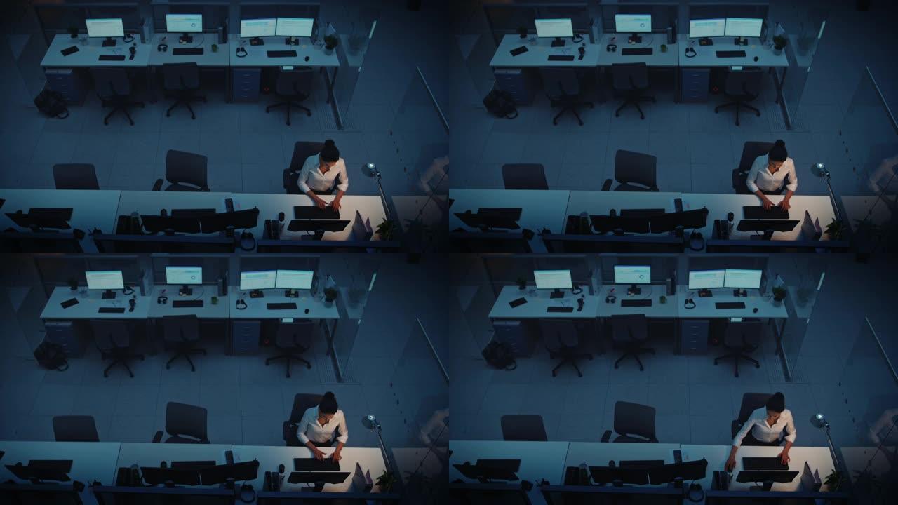 独自在办公室深夜工作: 女商人使用台式计算机，分析，使用文档，解决问题，完成项目。高架高角度射击