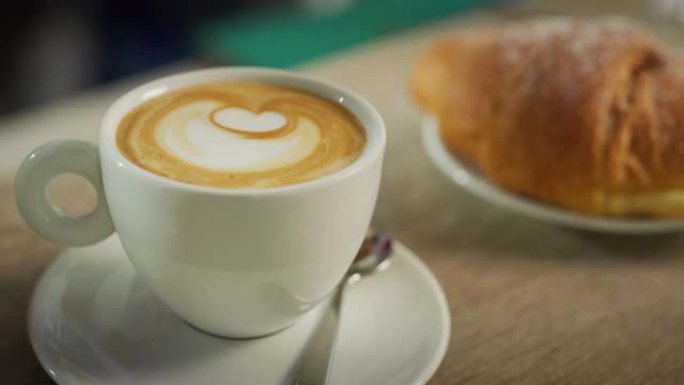 一杯咖啡和一小盘羊角面包制成的精美构图的肖像，而酒保则倒入caffee。