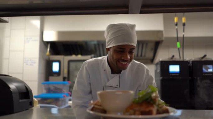 开朗的黑人厨师在一家餐厅准备点菜，准备将其带到柜台上的顾客手中