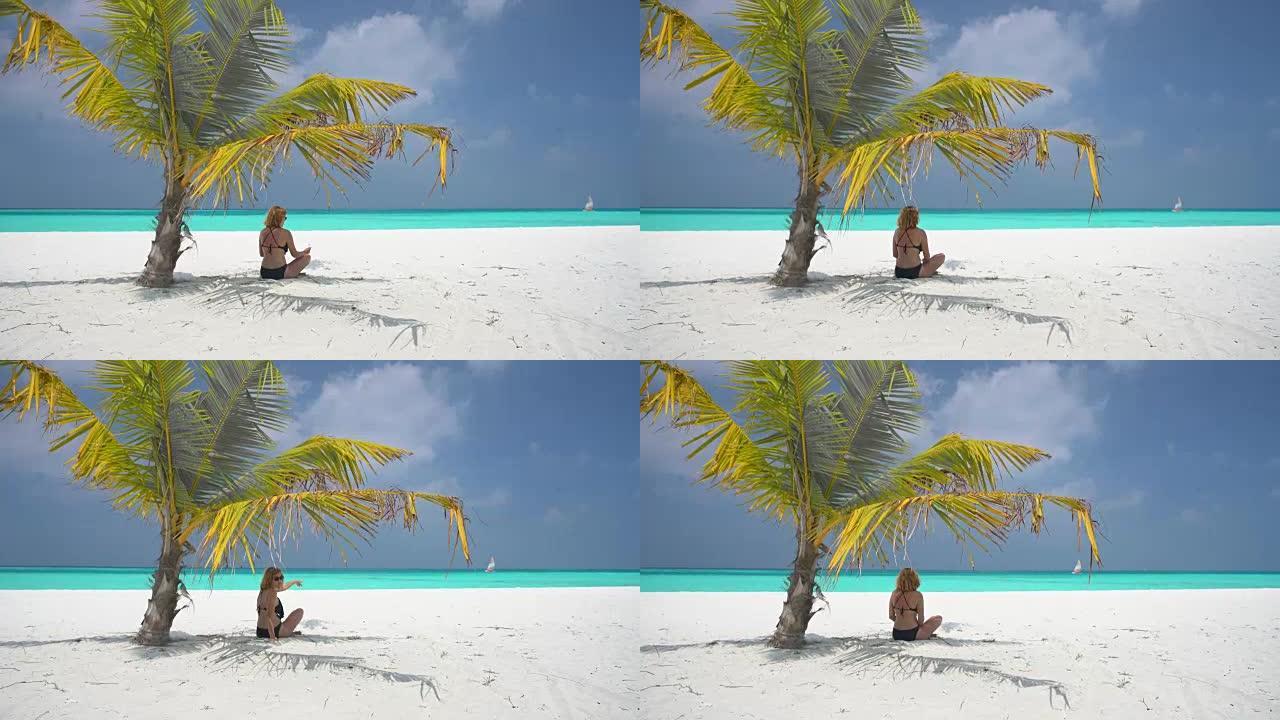 女士女士在马尔代夫阳光明媚的热带海洋海滩上的棕榈树树荫下放松