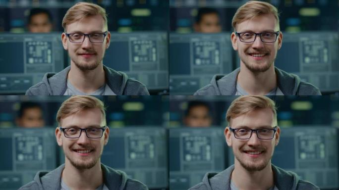 一位聪明英俊的IT专家戴着眼镜的肖像对着镜头迷人地微笑。在技术研究数据中心中带有屏幕的背景下未聚焦的