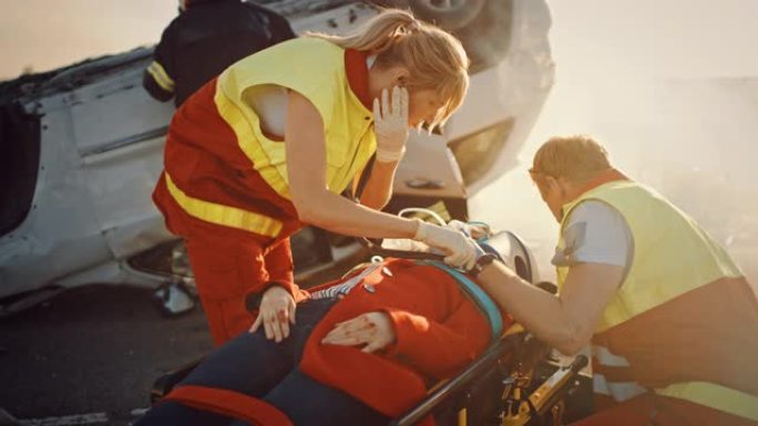 在车祸事故现场: 消防员救援队将女性受害者从翻车中拉出，他们小心翼翼地使用担架，将其交给急救人员