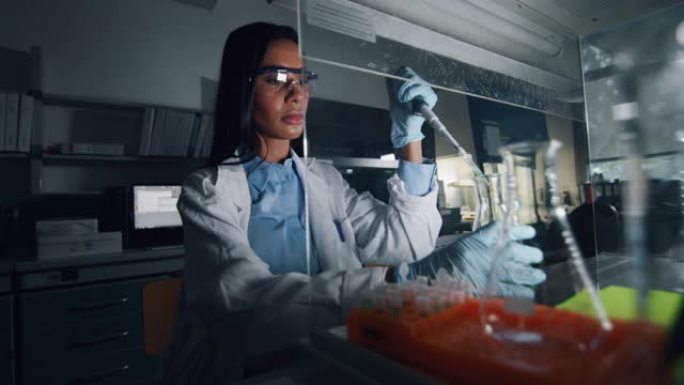 深色皮肤的肖像女科学家正在用移液管分析液体，以提取实验室试管中的DNA和分子