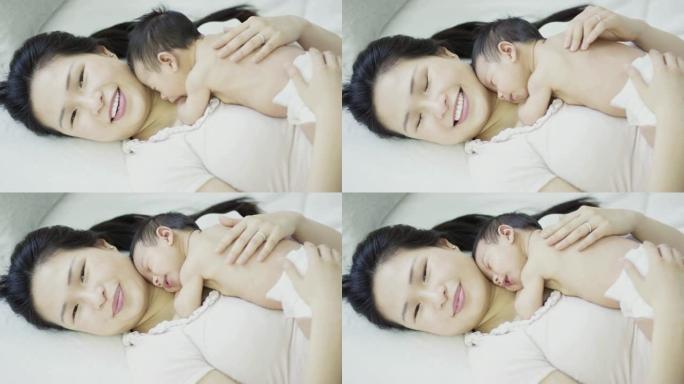 亚洲母亲与刚出生的儿子躺在胸前睡觉