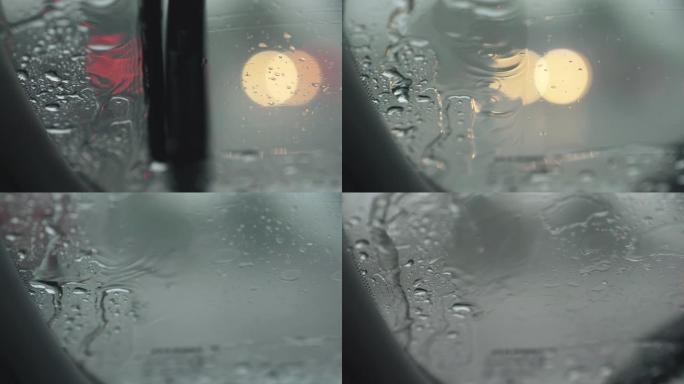在雨中工作的汽车挡风玻璃雨刷。从挡风玻璃上可以看到过往汽车交通的模糊灯光。水沿着挡风玻璃流下。UHD