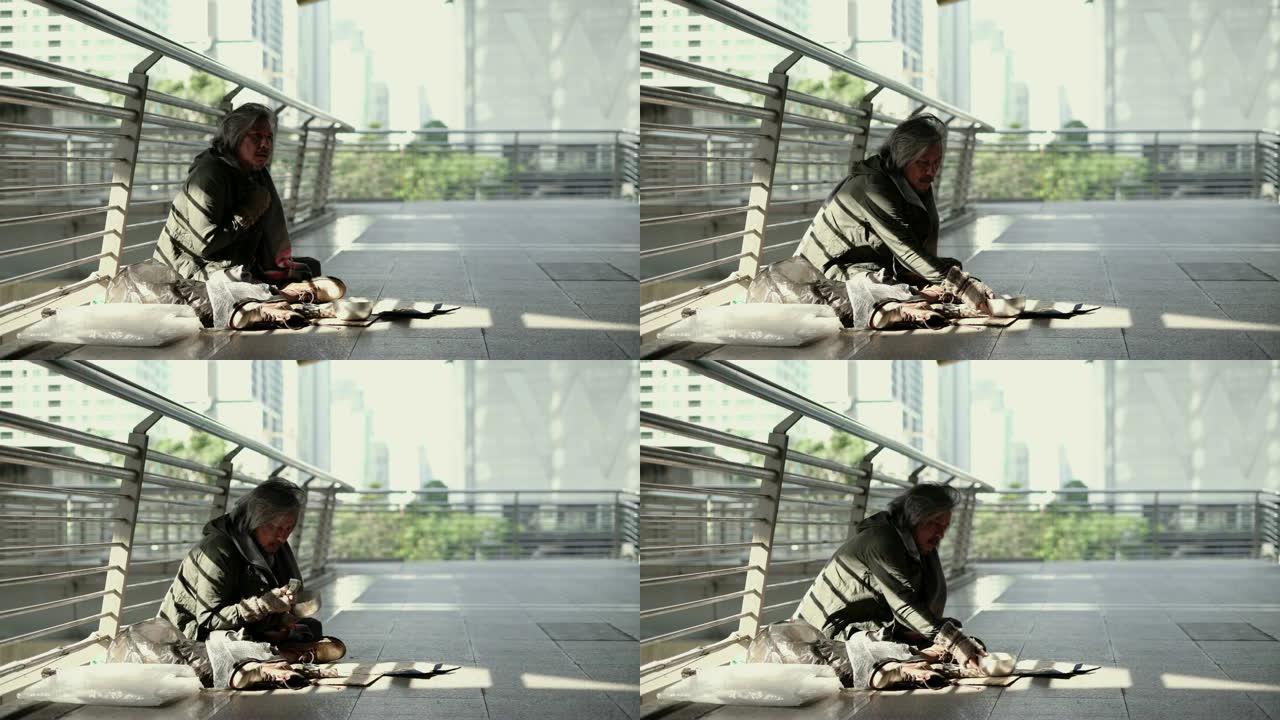 无家可归的老人坐在人行道上。