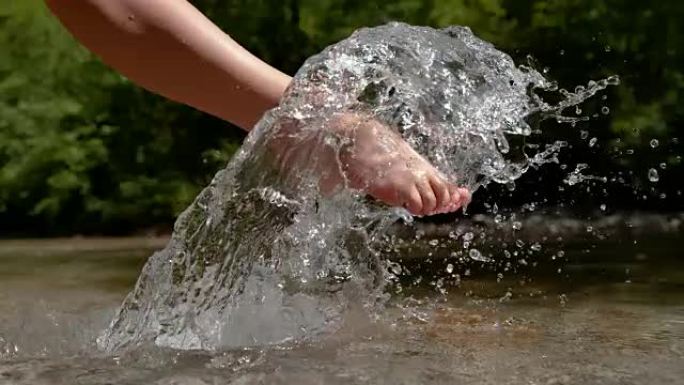 慢动作: 顽皮的年轻赤脚女人踢玻璃山河水。