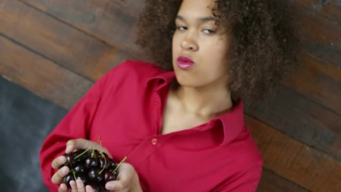 年轻黑人妇女拿着樱桃的肖像