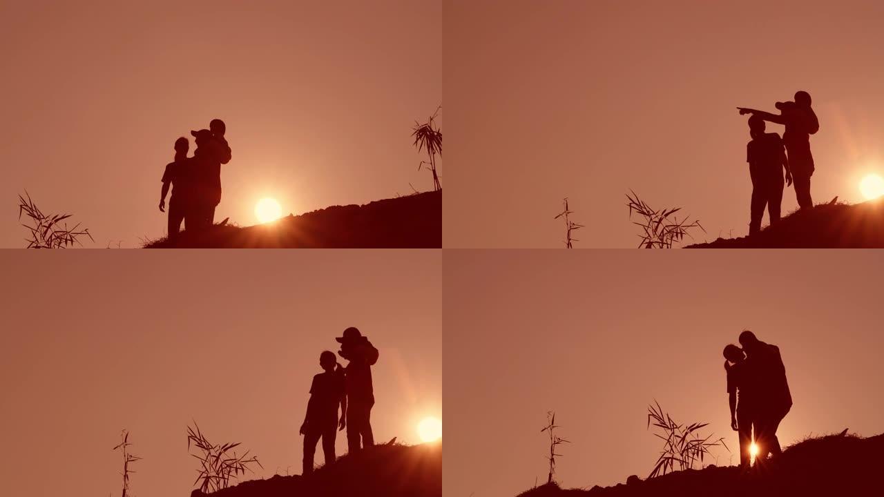 剪影幸福的家庭父亲母亲和儿子在父亲的肩膀上走在日落时分的大自然中