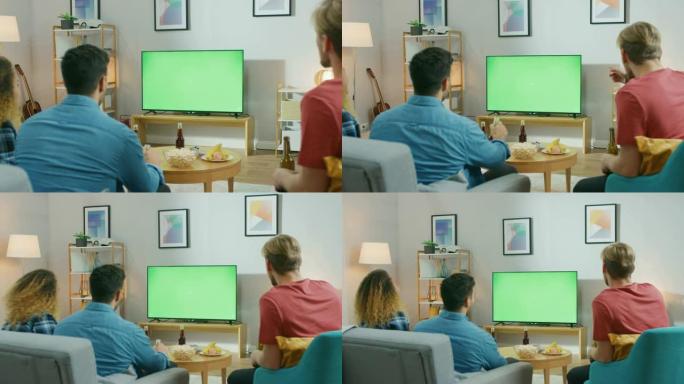 三个体育迷坐在客厅的沙发上观看绿色色键屏幕电视重要比赛，玩得开心，喝饮料和吃零食，为他们的球队加油。