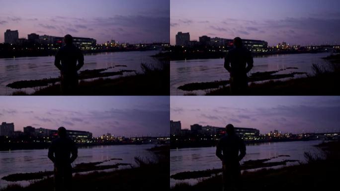 日落时分的河边。背景中的城市天际线。欣赏风景的人