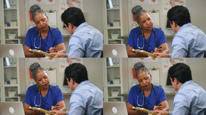 护士在给病人看笔记时与病人交谈