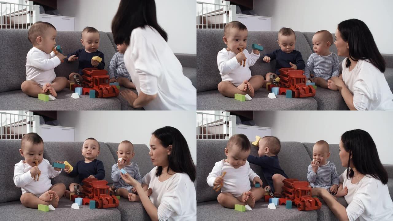 亚洲三胞胎婴儿在沙发上玩木制玩具